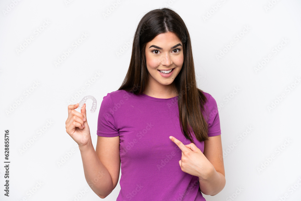 Young Brazilian woman holding invisible braces isolated on white background with surprise facial expression Young Brazilian woman holding invisible braces isolated on white background with surprise facial expression