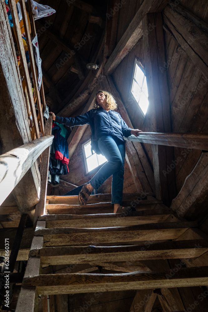 Enkoping, Sweden A woman descends wooden steps in an old barn  at a thrift store.