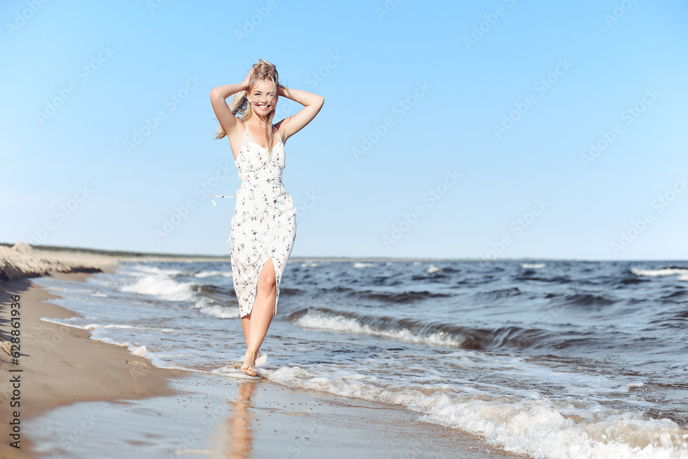 Happy blonde beautiful woman having fun on ocean beach while dancing in waves Happy blonde beautiful woman having fun on ocean beach while dancing in waves