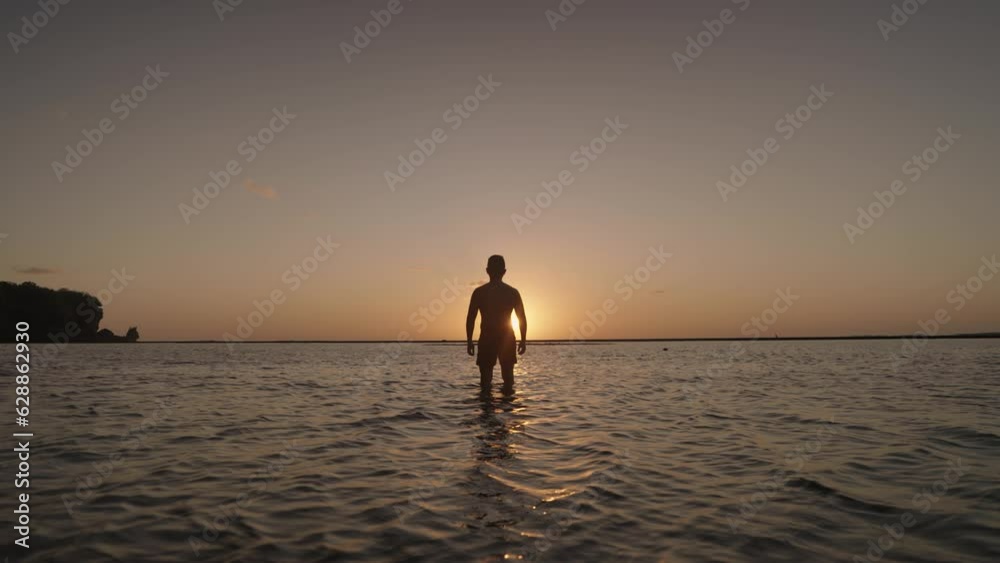Silhouette of Man Walking on The Beach toward the Sunset with Dramatic Colorful Sky - Freedom, Motivation and Hopefulness Silhouette of Man Walking on The Beach toward the Sunset with Dramatic Colorful Sky - Freedom, Motivation and Hopefulness