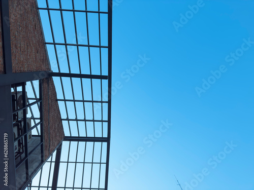 A building with a black H-beam steel frame  combined with red bricks against a backdrop of blue sky