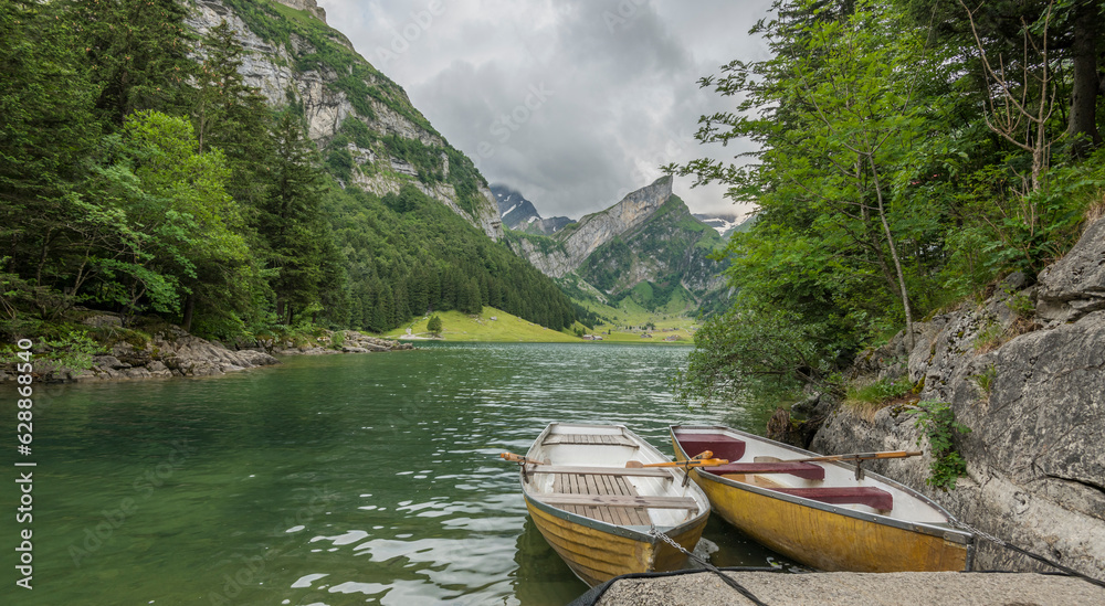 Summer view on the Bachalpsee, an alpine lake in Switserland. Surrounded by high steep mountains and forest. Rowing boats in the foreground. Hiking tour in the Swiss mountains. rainy day.