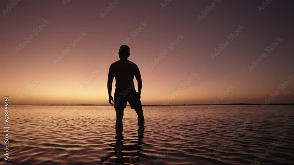 Silhouette of Man Walking on The Beach toward the Sunset with Dramatic Colorful Sky - Freedom, Motivation and Hopefulness Silhouette of Man Walking on The Beach toward the Sunset with Dramatic Colorful Sky - Freedom, Motivation and Hopefulness