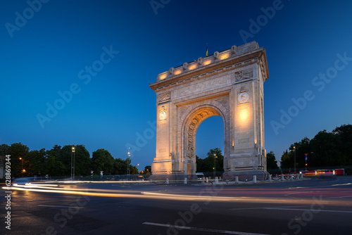 Arch of Triumph in Bucharest, travel to Romania. Long exposure photo with traffic lights in the morning blue hour sky. Beautiful landscape photo of Bucharest.