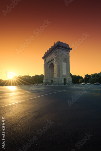Sunrise in Bucharest. Wide photo during a spectacular summer sunrise with the silhouette of Arch of Triumph landmark in Bucharest. Travel to Romania. © Dragoș Asaftei