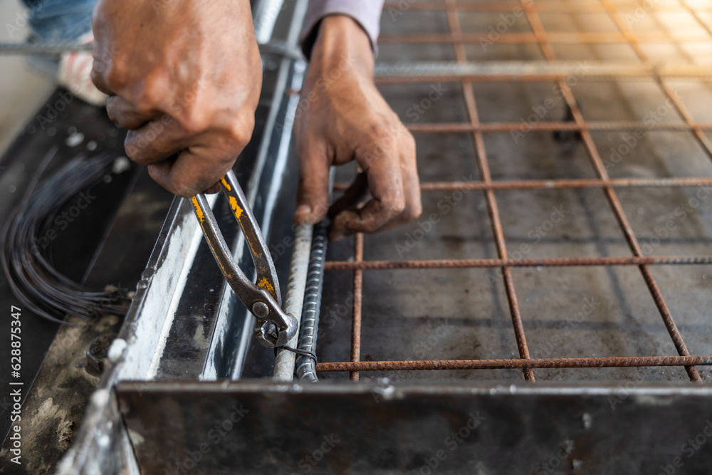 Reinforced concrete structures. Construction worker uses pilers tools and steel tying wire to fasten steel rods of concrete wall at Heavy Industry Manufacturing Factory. Prefabricated concrete walls