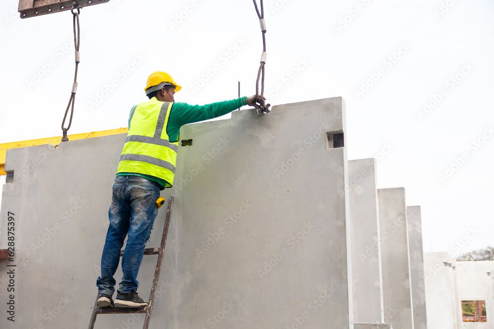 Reinforced concrete structures. Man construction worker control large crane for placing precast concrete panels at Heavy Industry Manufacturing Factory Reinforced concrete structures. Man construction worker control large crane for placing precast concrete panels at Heavy Industry Manufacturing Factory