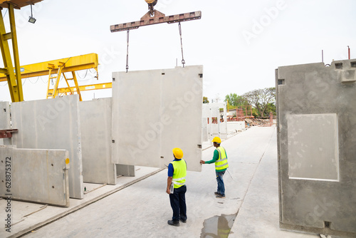 Reinforced concrete structures. Man construction worker control large crane for placing precast concrete panels at Heavy Industry Manufacturing Factory photo