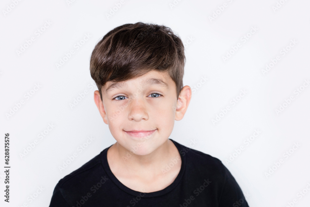 Portrait of a cute innocent boy schoolboy 8 years old, the boy smiles in a black t-shirt on a light background, he is happy that parents love him and accept him as he is Portrait of a cute innocent boy schoolboy 8 years old, the boy smiles in a black t-shirt on a light background, he is happy that parents love him and accept him as he is