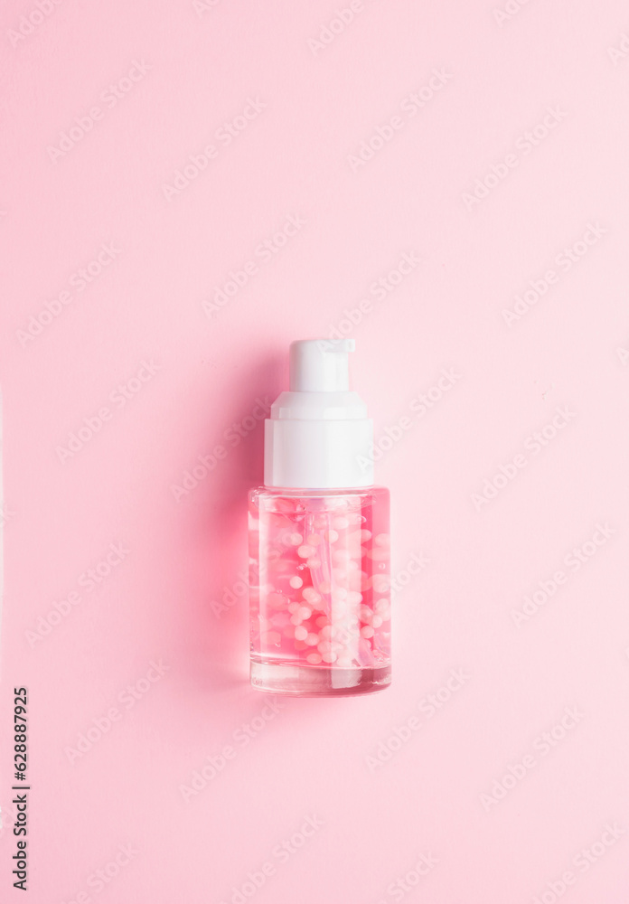 Bottle with liquid cosmetic product with pink molecules on a pink background Bottle with liquid cosmetic product with pink molecules on a pink background