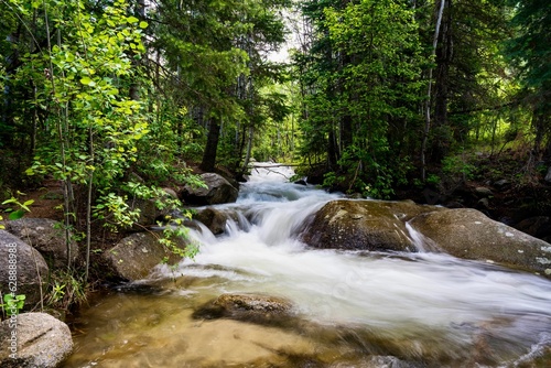 Tranquil stream flows through a picturesque landscape with large rocks and trees