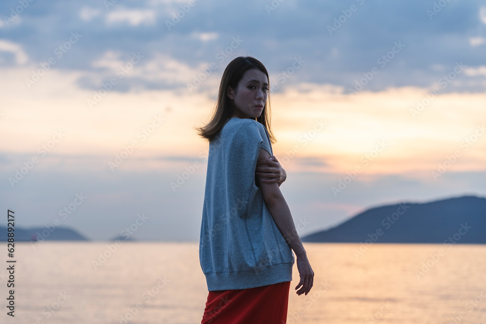 夕暮れの海にいる女性
