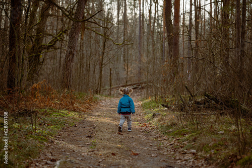 little girl running in autumn forest, back view. little kid running in autumn forest