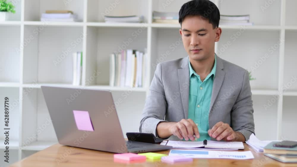 Serious businessman working on paperwork on laptop and financial accounting documents with calculator on office desk. Serious businessman working on paperwork on laptop and financial accounting documents with calculator on office desk.