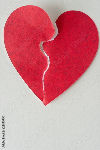 broken paper heart - artfully torn down the center and joined feebly on blank paper photo