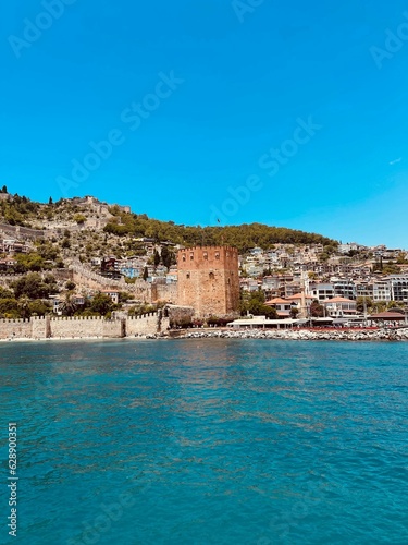 Fototapeta Naklejka Na Ścianę i Meble -  Stunning seaside view of the Alanya Red Tower in Turkey with boats near the shoreline