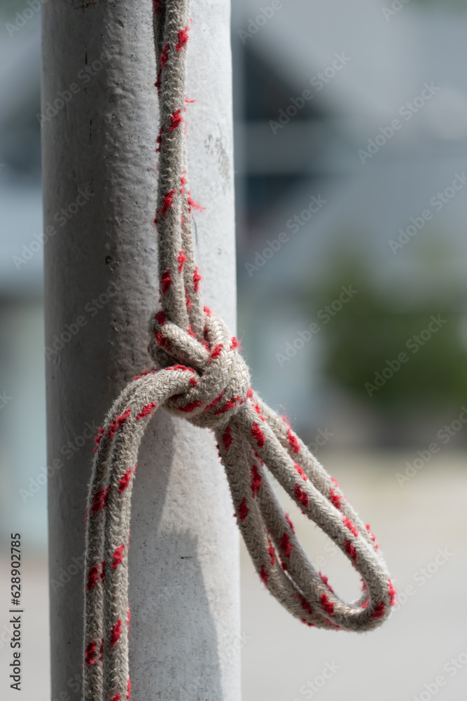Naklejka premium knotted rope hanging from an old painted pole outdoors (abstract background)