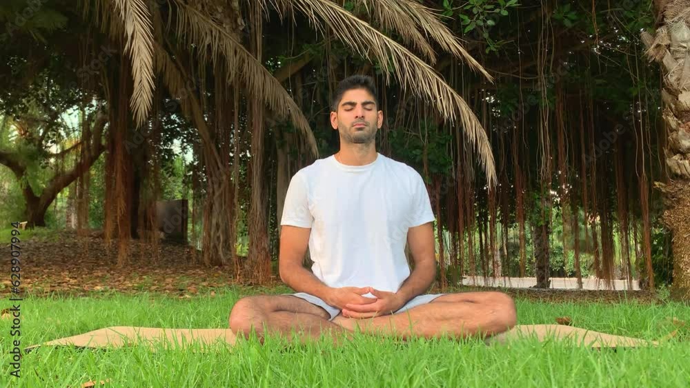 Joven indio practicando técnicas de respiración. Sesión sobre colchoneta de yoga en el parque. Relax al aire libre para una mejor salud. Ejercicios de enfoque por la mañana en verano en Tenerife