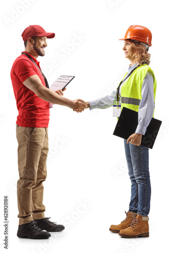 Full length profile shot of a delivery worker shaking hand with a female engineer