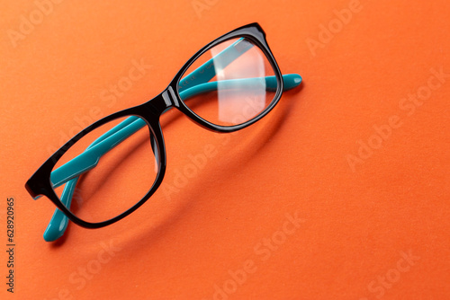 Glasses for vision on an orange background. Optical store, glasses selection, eye test, vision examination at optician