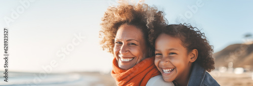 Portrait of happy African American grandmother and granddaughter on the beach. Concept of friendly family.