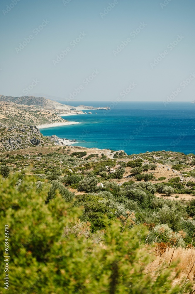 Landscape featuring a stunning beach on the horizon with crystal clear blue waters in Greece