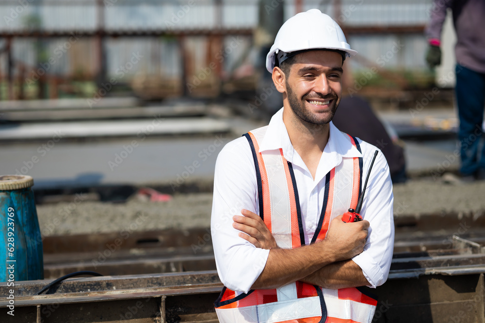 Portrait building and construction worker, Hiapanic latin male wearing safety hard hat helmet standing with arms crossed at construction site and looking at camera Portrait building and construction worker, Hiapanic latin male wearing safety hard hat helmet standing with arms crossed at construction site and looking at camera