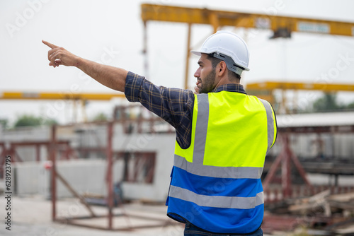 radio transmitter. Hispanic latin architect construction Engineering man in hardhat talking on walkie talkie at factory facilities. Heavy Industry Manufacturing Factory. Prefabricated concrete walls