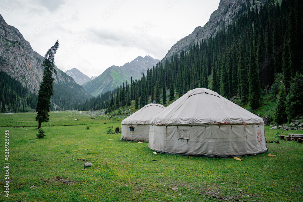 Two Kyrgyz yurts on grass in middle of the mountains. Yurts are traditional national buildings of local residents