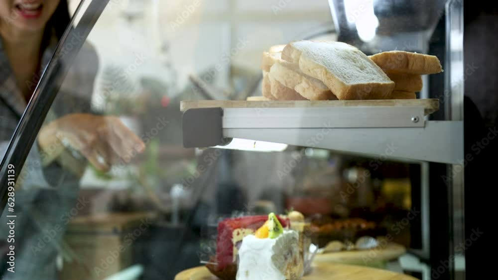 4k, unfocus customer order bakery take away in cabinet, candid camera snapshot through a piece of cake, delicious homemade bread bakery in coffee shop ready to serve customer, variety products in cafe