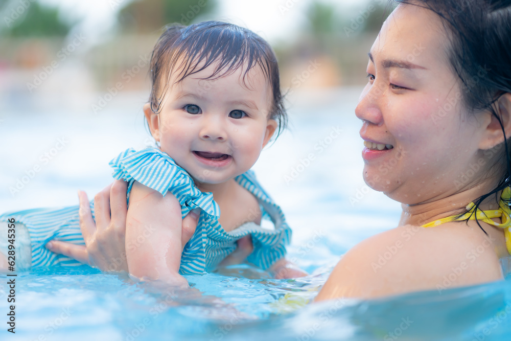 happy and beautiful Asian woman holding her little baby girl playful