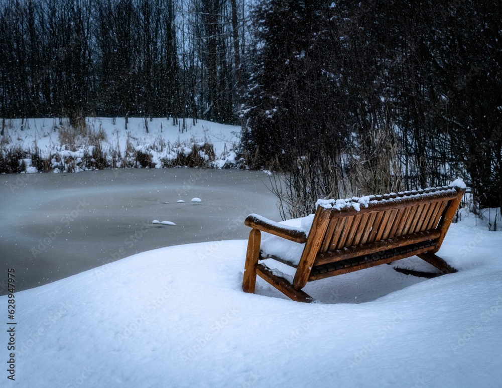 a bench sitting on the snow covered beach next to a frozen pond