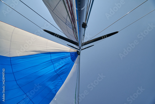 White sails and blue sky in the tropics. Sailing yacht on vacation in the ocean. Mast, boom, halyard, wind-filled sails - jib, spinnaker, genoa, mainsail. photo
