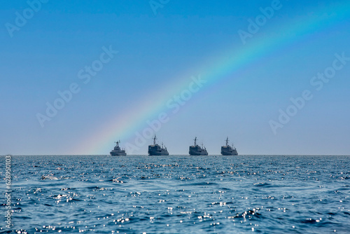 Warships at sea with a rainbow in the sky