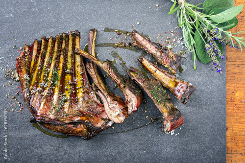 Traditional barbecue venison ribs with herbs and spice served as top view on a gray board