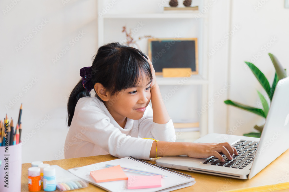 A girl who came back from school is sitting doing her homework, using the computer to find homework information in the reception room. A girl who came back from school is sitting doing her homework, using the computer to find homework information in the reception room.