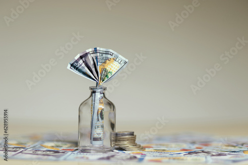 billete de 100 dolares dentro de un frasco de vidrio, sobre mas dolares en la meza, concpeto de ahorros y finanzas photo