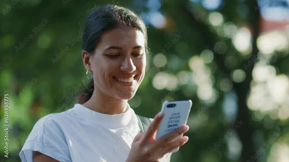Young caucasian female walking and looking at her phone with a smile