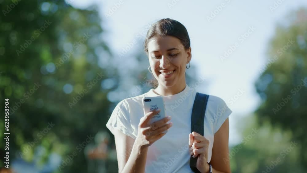 Young caucasian female walking and looking at her phone with a smile Young caucasian female walking and looking at her phone with a smile