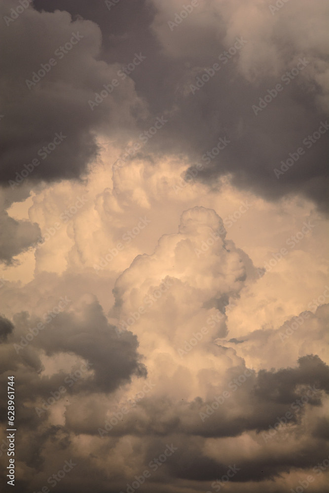 large white-gray clouds illuminated by the orange setting sun