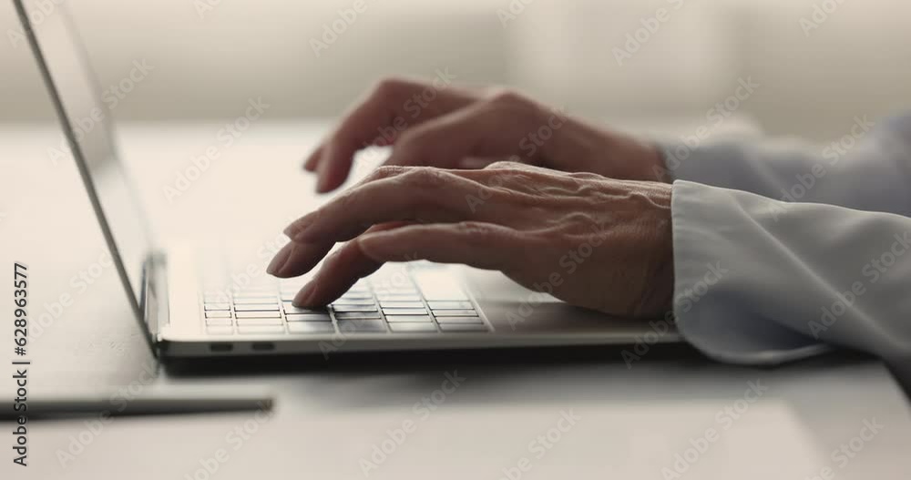 Hands and fingers of professional woman pressing buttons on keyboard, typing on laptop computer placed on work office table, using modern technology, digital gadget for business. Close up cropped shot