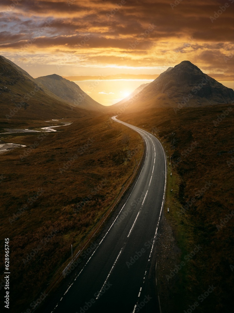 a road winds through a mountain with a beautiful sunset in the background