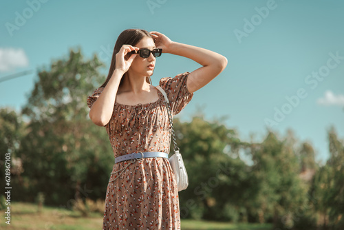 A young beautiful girl in the park on a summer day looks into the distance.
