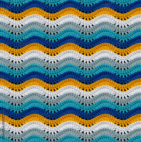 Seamless knitted pattern in the form of openwork waves is crocheted with threads of bright colors. Cotton yarn. Volumetric style.