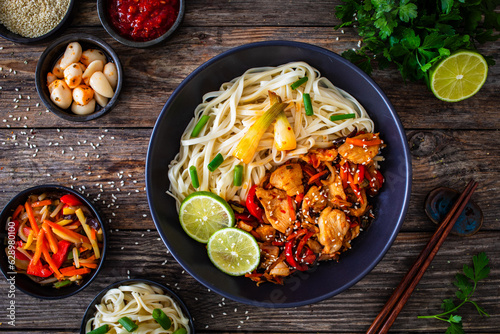 Asian food - chicken nuggets, noodles and stir fried vegetables on wooden table 