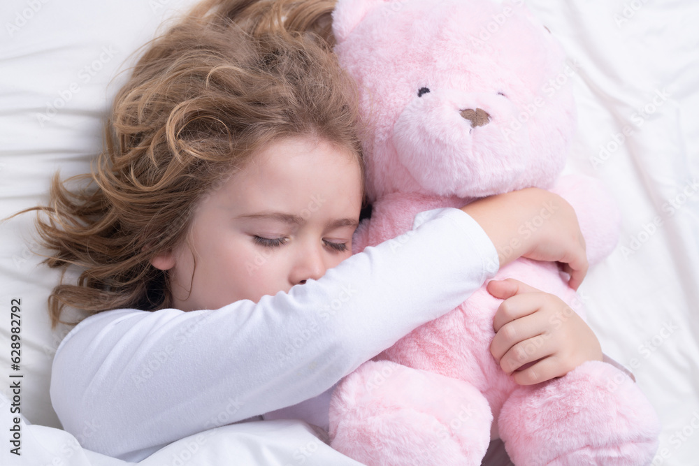 Good morning sleep. Little boy sleeping in bed with a toy teddy bear. Cute kid sleeping well alone in bed under blanket. Kid lying on comfort pillow, adorable small child rest asleep.