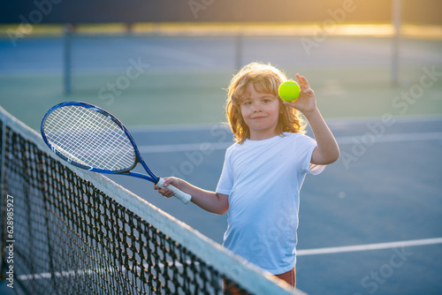 Tennis kids. Child playing tennis. Sport child with racket on tennis playground during training in summer. © Volodymyr