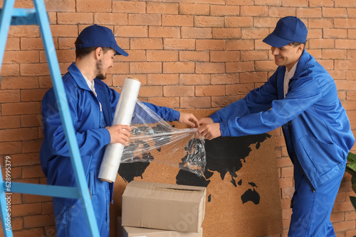 Male movers wrapping world ...