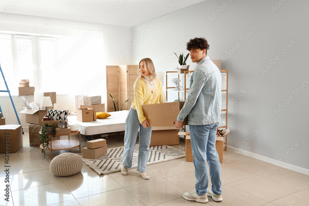 Young couple carrying box in bedroom on moving day Young couple carrying box in bedroom on moving day
