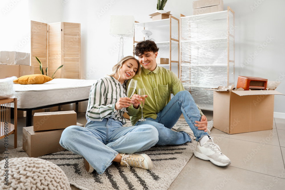 Young couple drinking champagne in bedroom on moving day